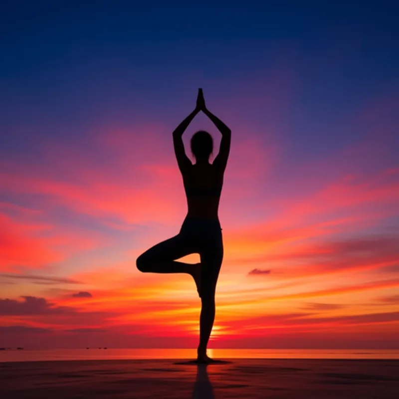 Silhouette of a person in tree pose with palms pressed together overhead, against a glowing sunset sky